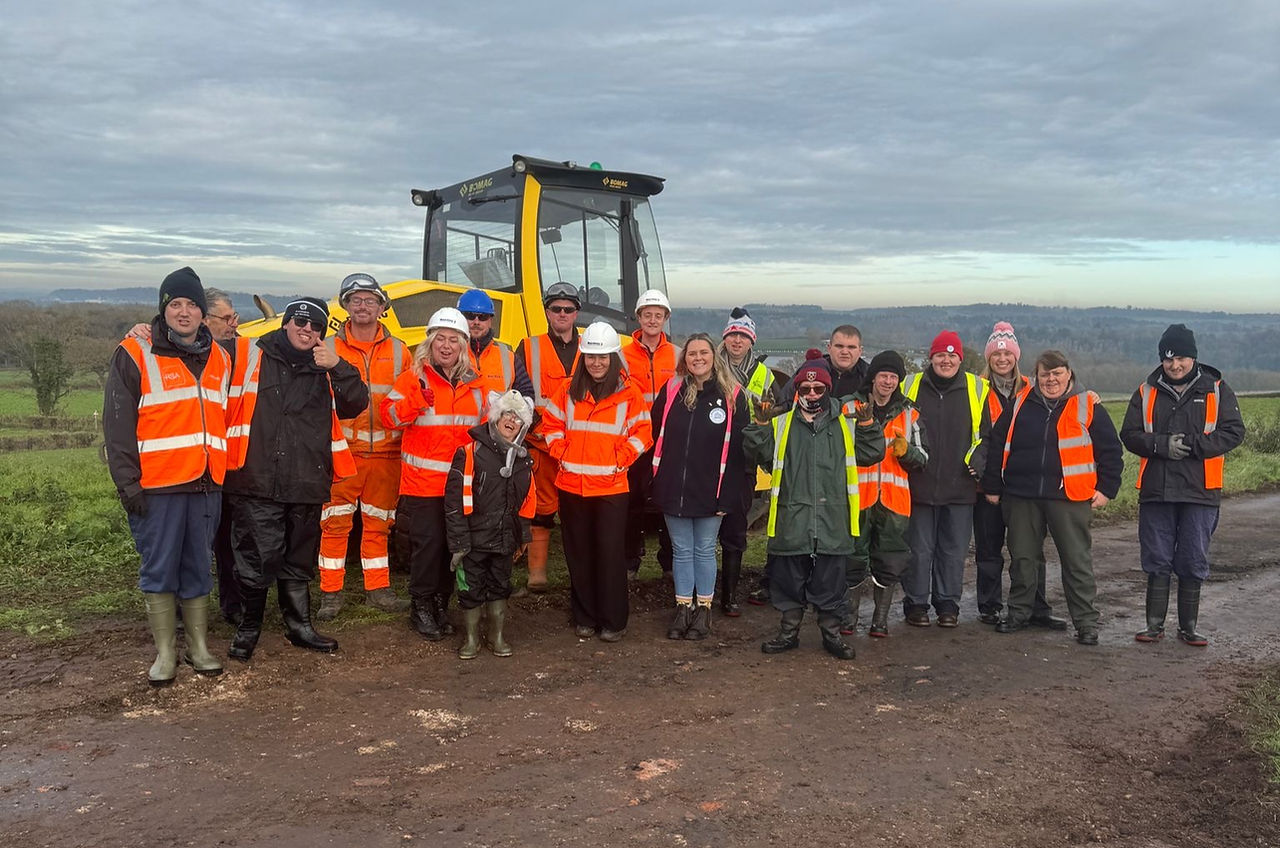 A group of people in construction PPE smiling for a photo on site