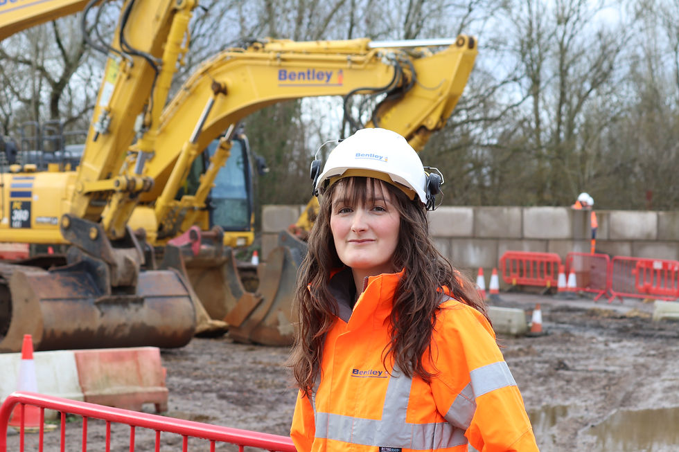 A female site worker stood next to an excavator